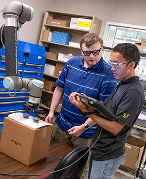 Two AURO students programming a robotic arm