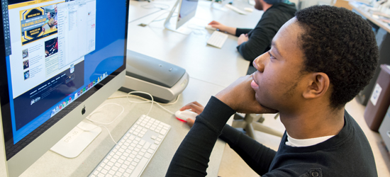 Student sitting at a computer contemplating the Millersville University website.