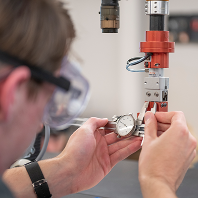 AURO student working in the lab with a dial caliper