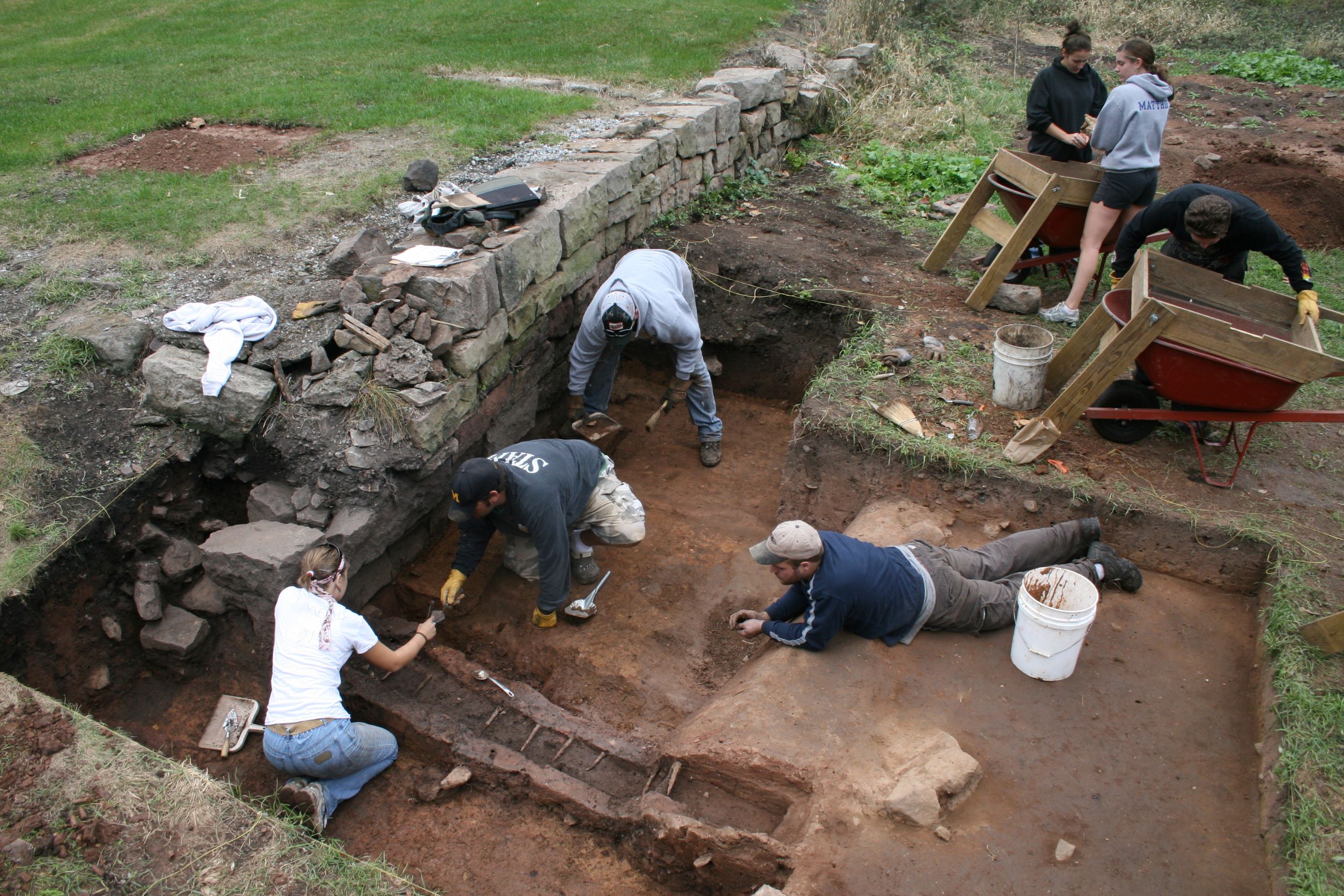 Archaeologists using a brush to expose a bottle broken insitu at the Elizabeth Furnace Plantation Site.