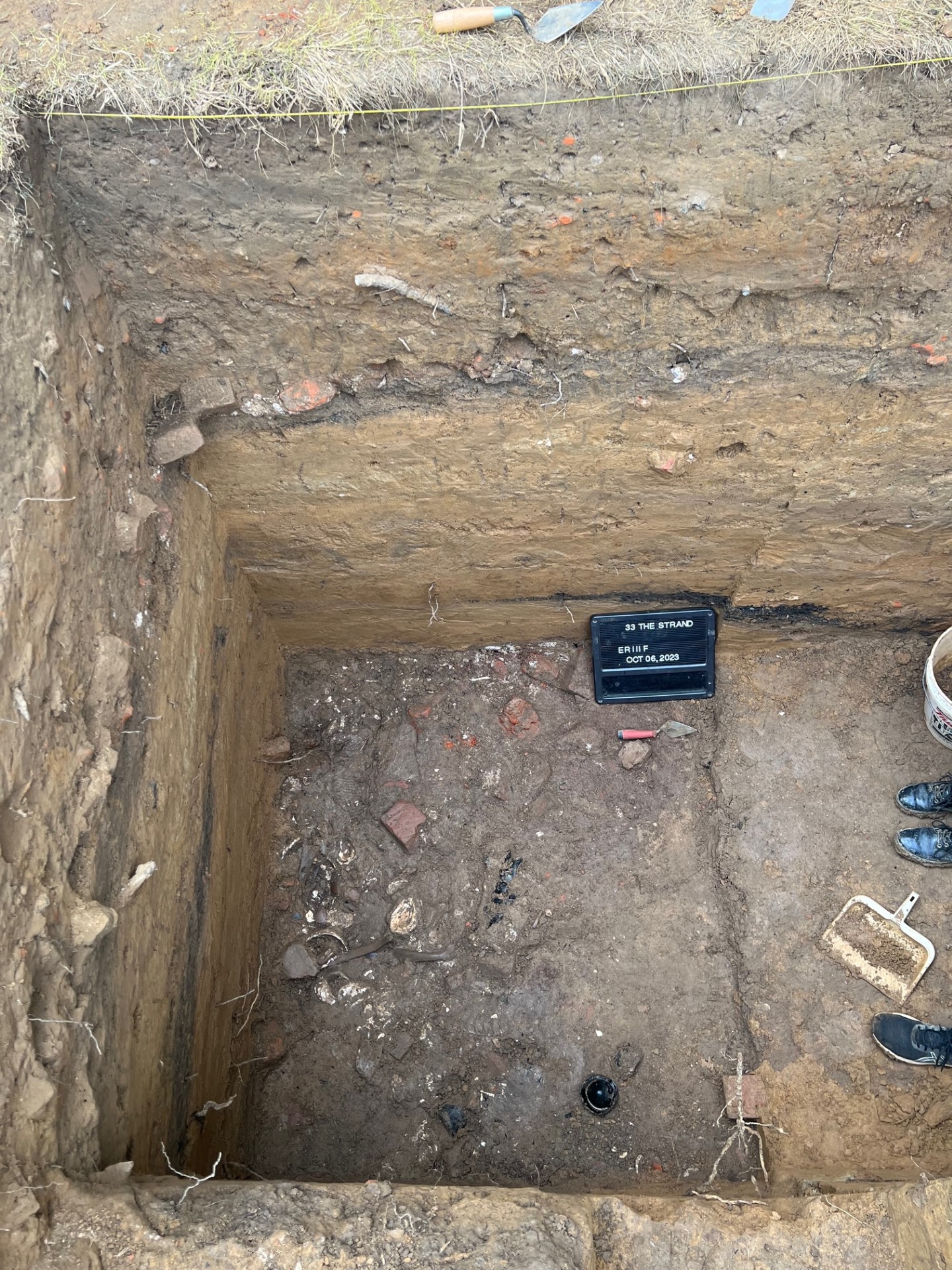 Archaeology dig pit showing artifacts and layers.