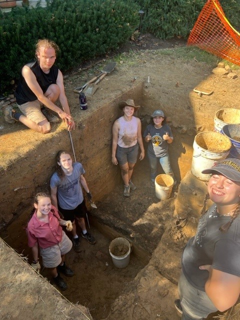Students pose around a dig pit.