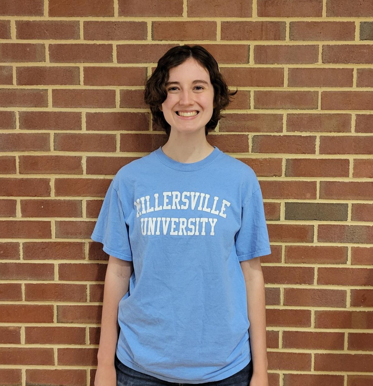 female student with short curly brown hair smiling