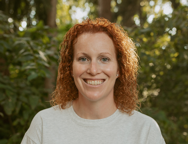 man with brown hair in a blue jacket by water