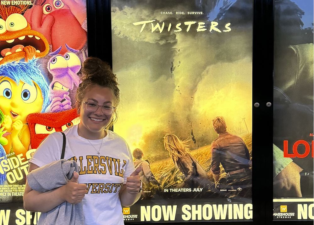 Meteorology student Willow Kint in front of Twisters poster.