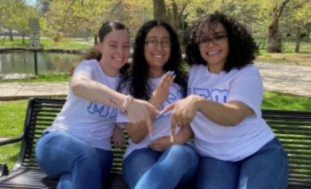 Three members of MU Sigma Upsilon Sorority sitting by Millersville University campus pond