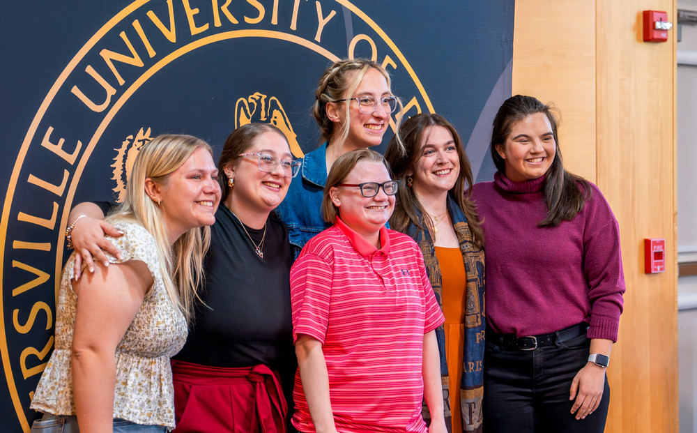 Six students stand close together in front of a Millersville University sign.