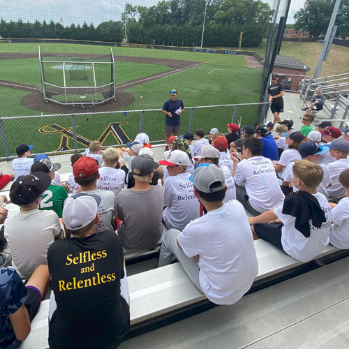 Group of students sitting on bleachers at a baseball field