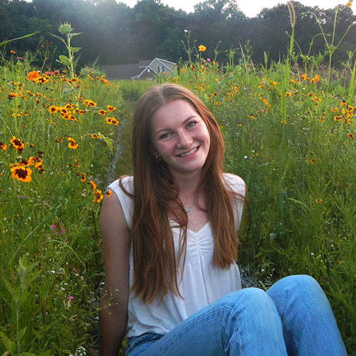Hailey Peirce sitting in a field of wild flowers