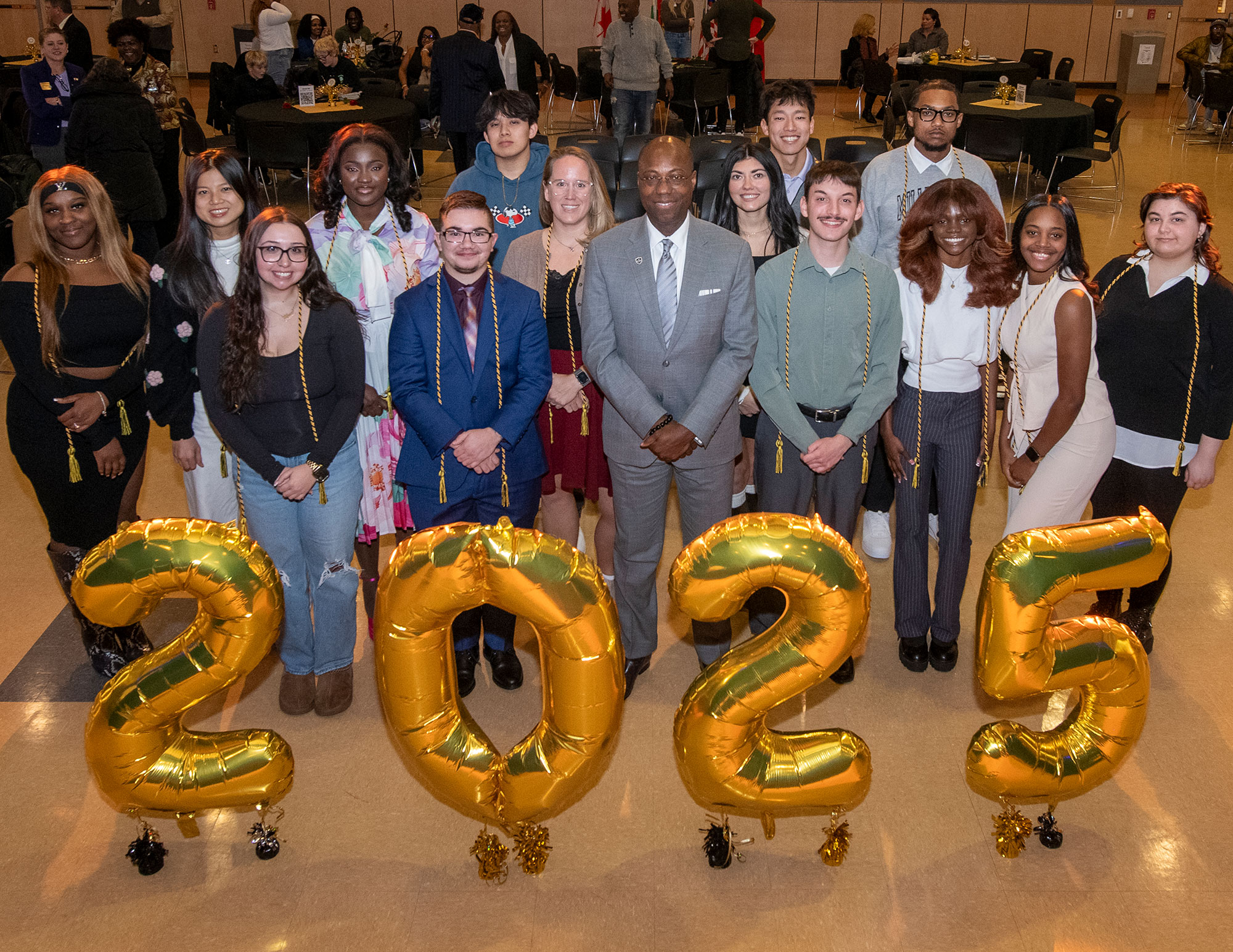 A group of people posing for a photo behind balloons in the shape of the current year, 2025