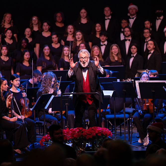 A person in a red shirt and black jacket with a group of people in the background
