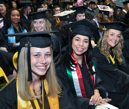 students at commencement smiling at the camera